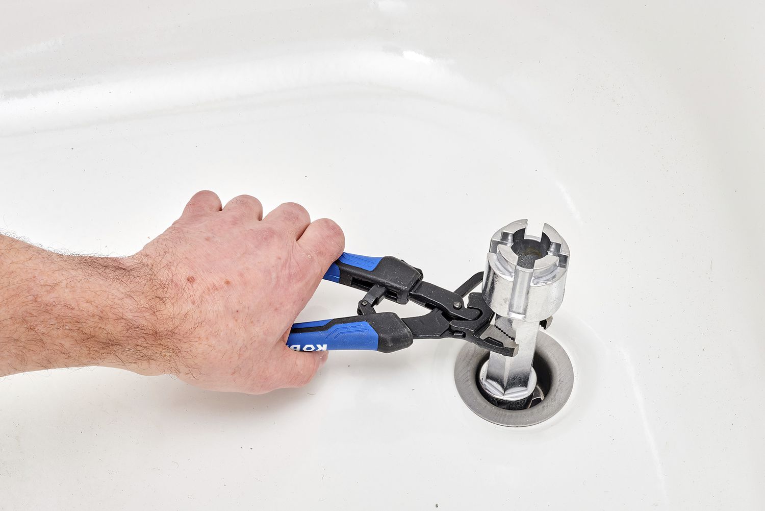 Adjustable wrench pulling out old drain fitting from bathtub