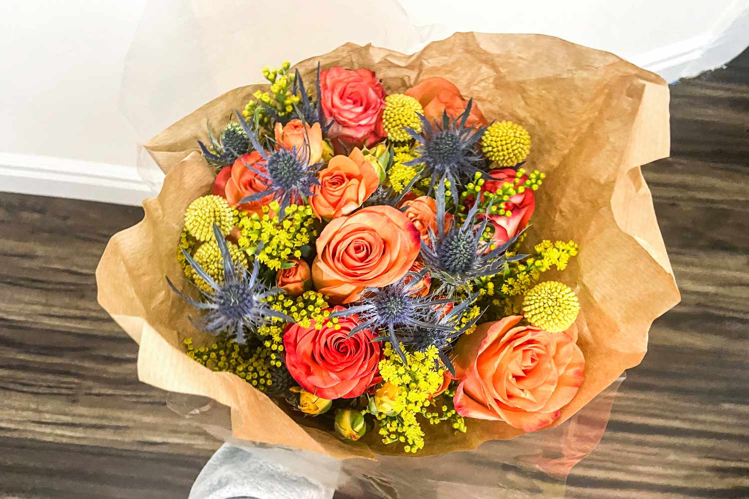 A person holding a bouquet from the UrbanStems service over a wooden floor