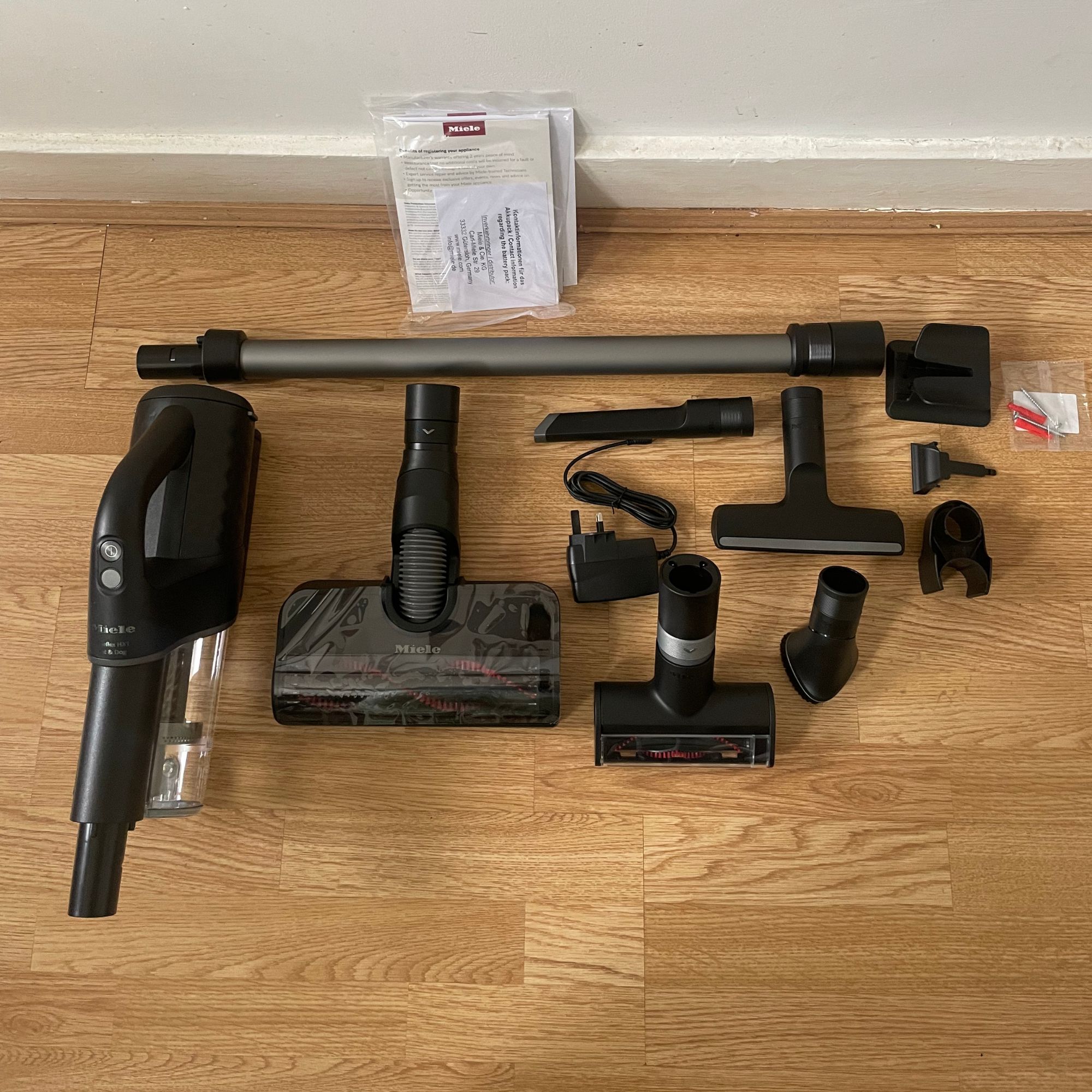 Miele DuoFlex HX1 components laid out on wooden flooring
