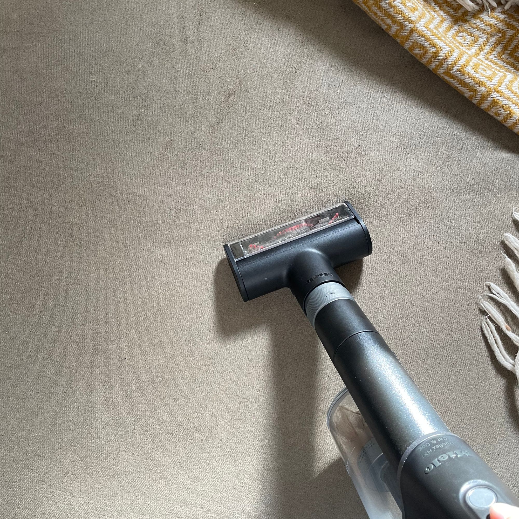 Miele DuoFlex electro brush cleaning a beige footstool