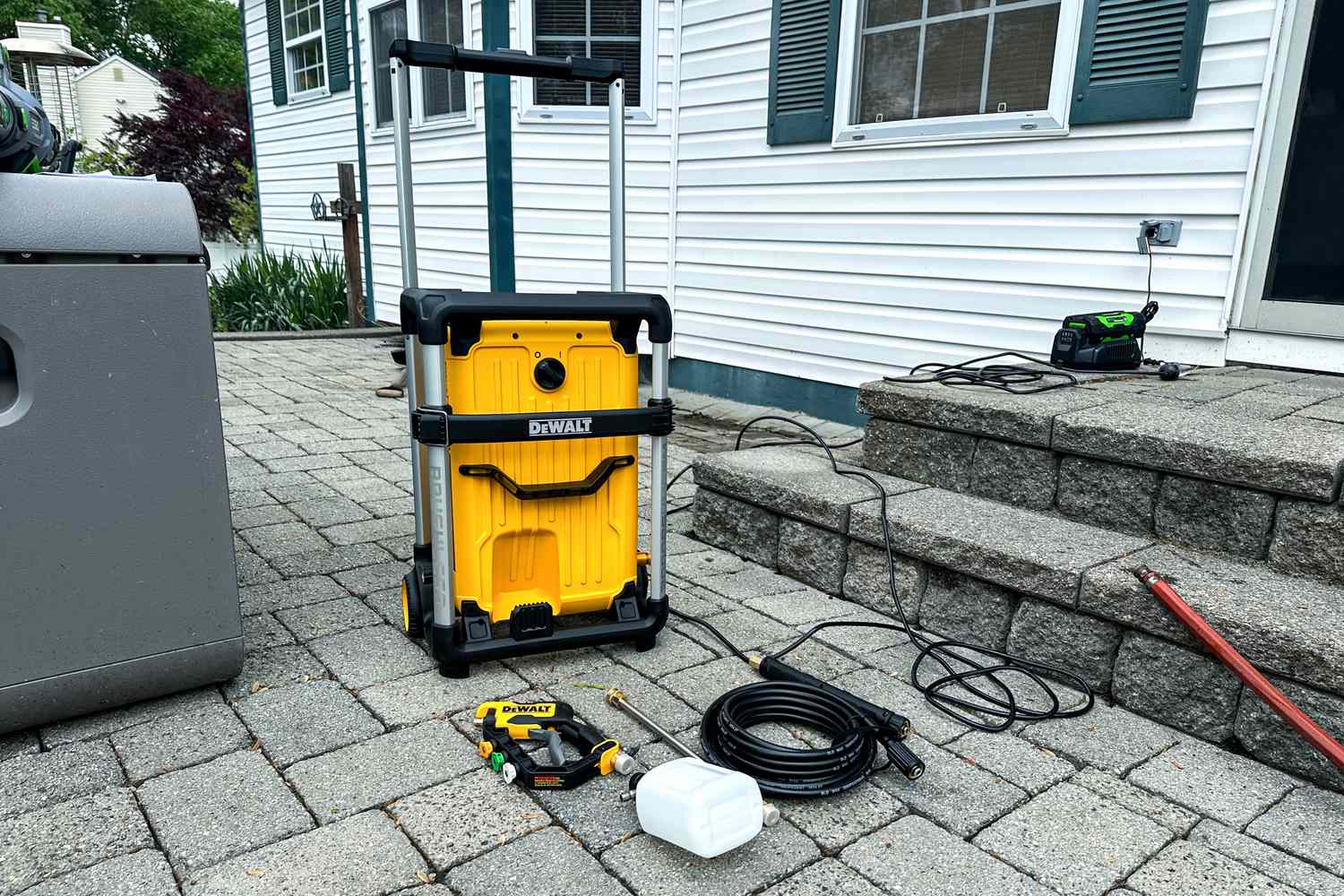 The parts of the DEWALT 3000 PSI 1.1 GPM 15 Amp Cold Water Electric Pressure Washer on a patio