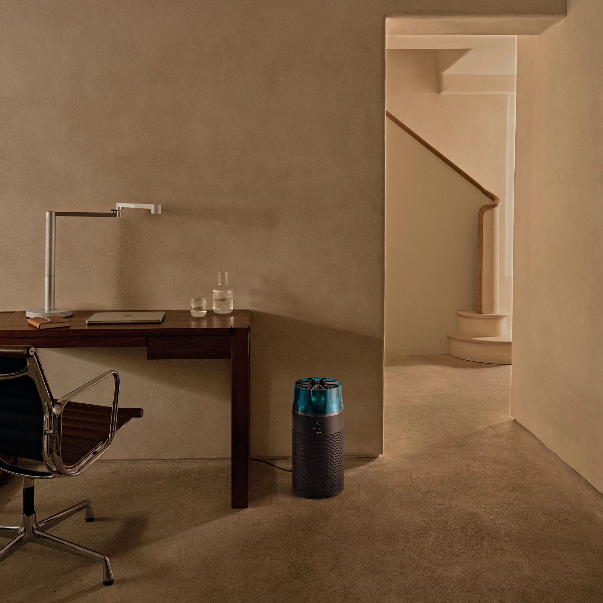 Dyson HushJet Air Purifier in a concrete-style office, sitting on the floor next to a desk and desk chair