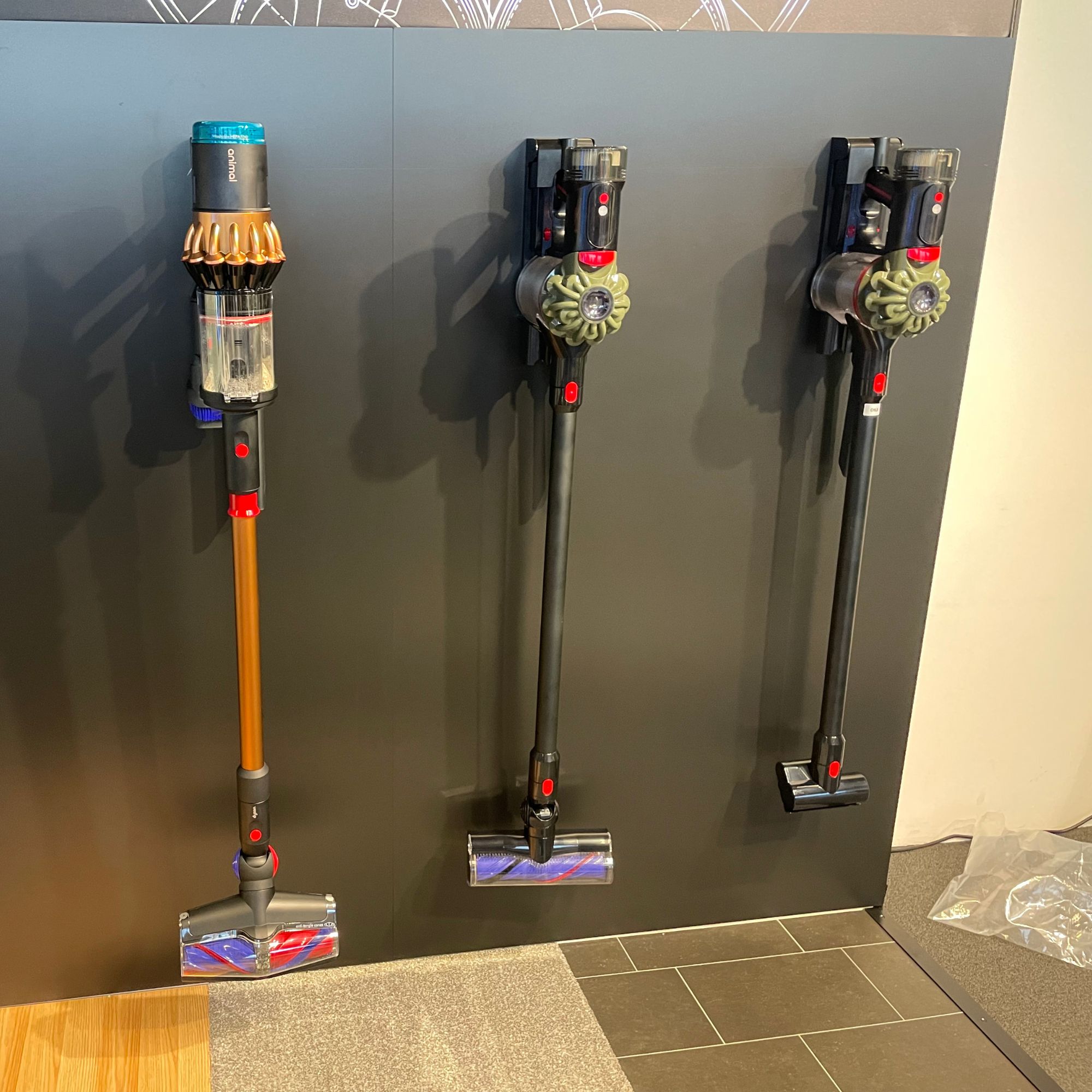 Dyson V8 Cyclone vacuum cleaners hanging on a black wall