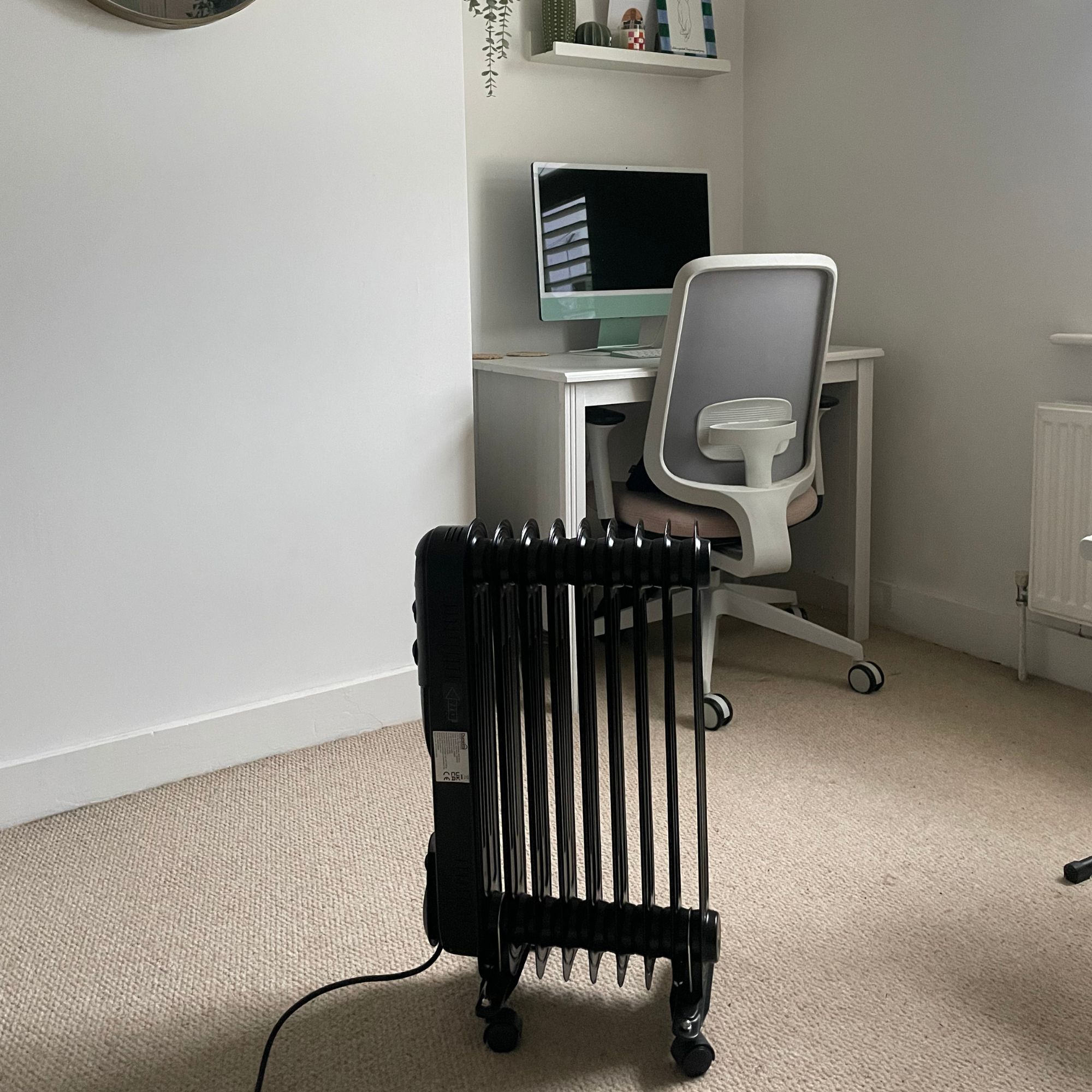 Dunelm oil-filled radiator standing in a white office area with a desk behind it