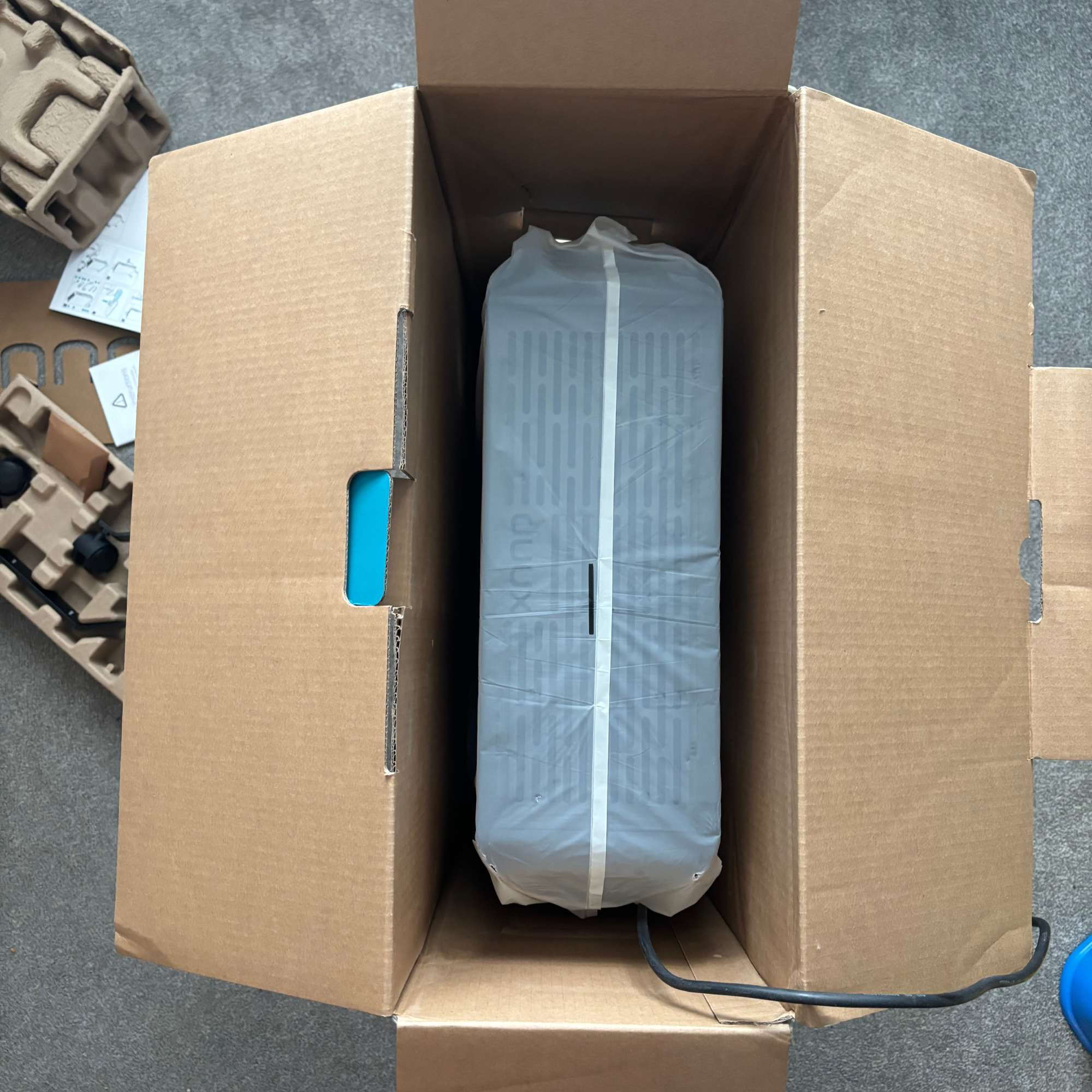 Rectangular cardboard box opened with Duux Edge Oil 2000W Oil-Filled Radiator securely placed beneath moulded cardboard