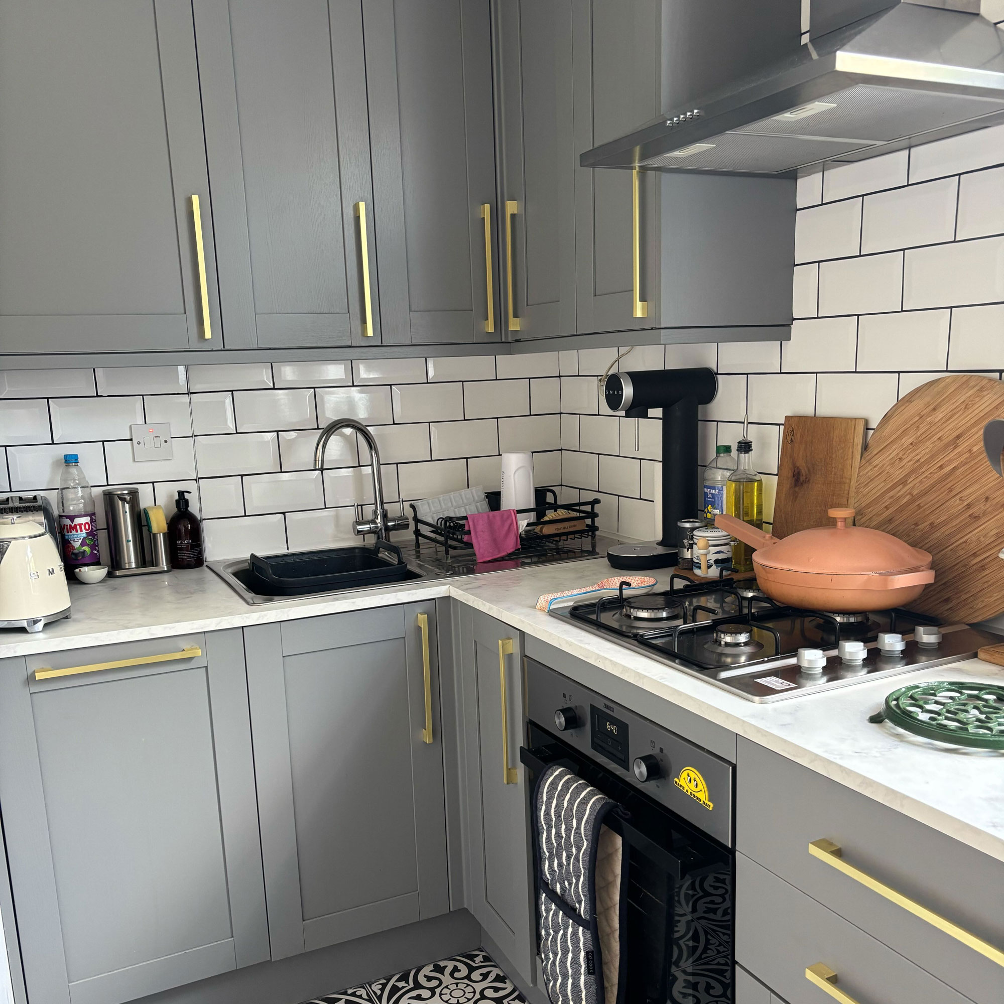 Green painted kitchen with gold handles and white countertops