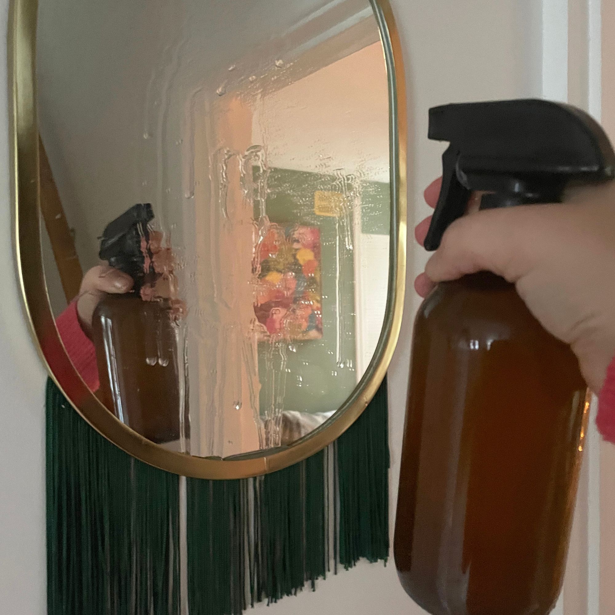 Spraying rice water onto a mirror with green tassles underneath it