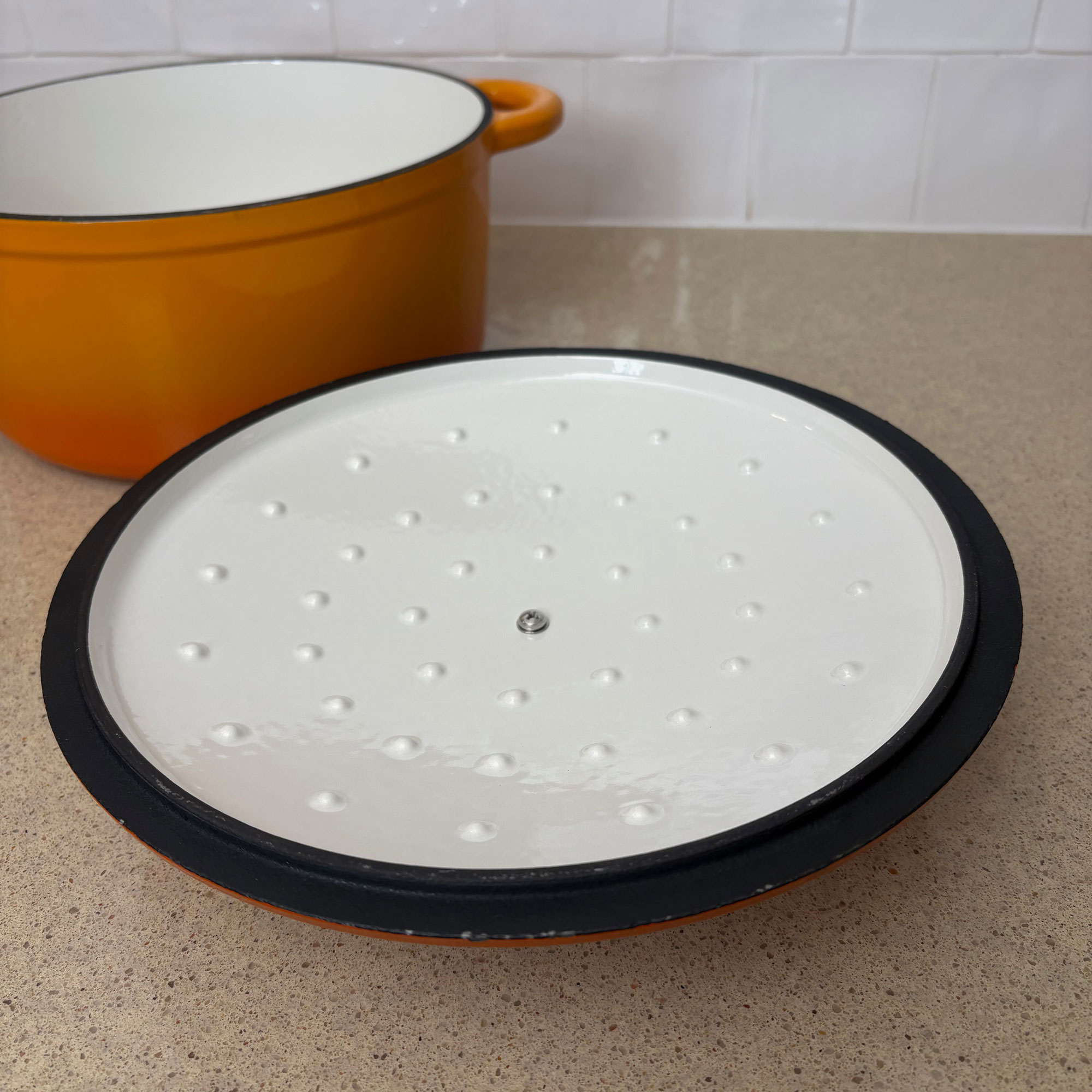 Orange cast iron pan with lid off and facing upwards.