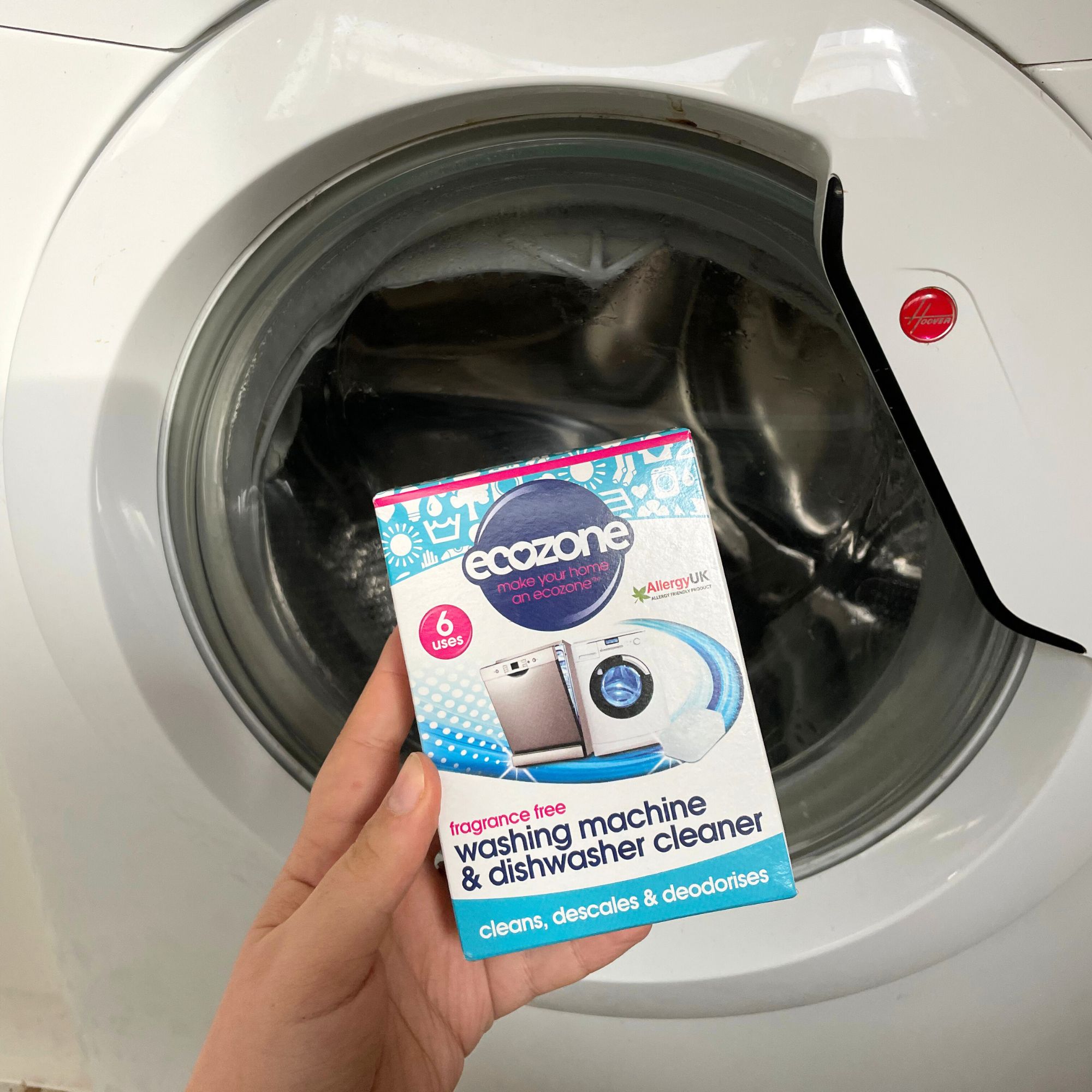 Holding a box of Ecozone washing machine cleaner in front of a washing machine