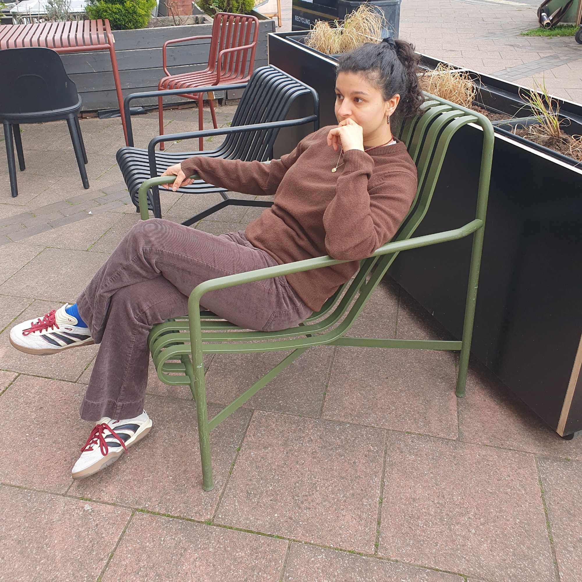Sara sitting on a green Palissade garden chair from HAY