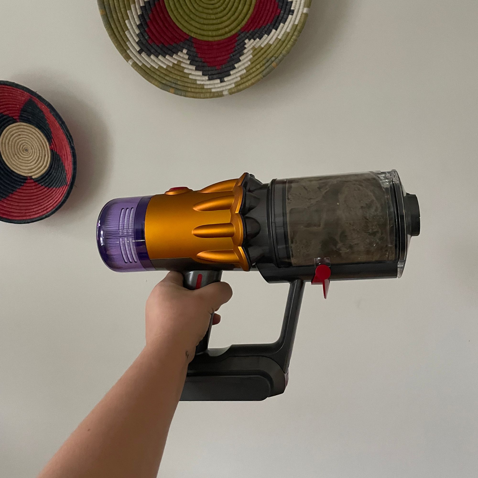 Hand holding up the dust bin of the Dyson V12 which is full of hair and debris