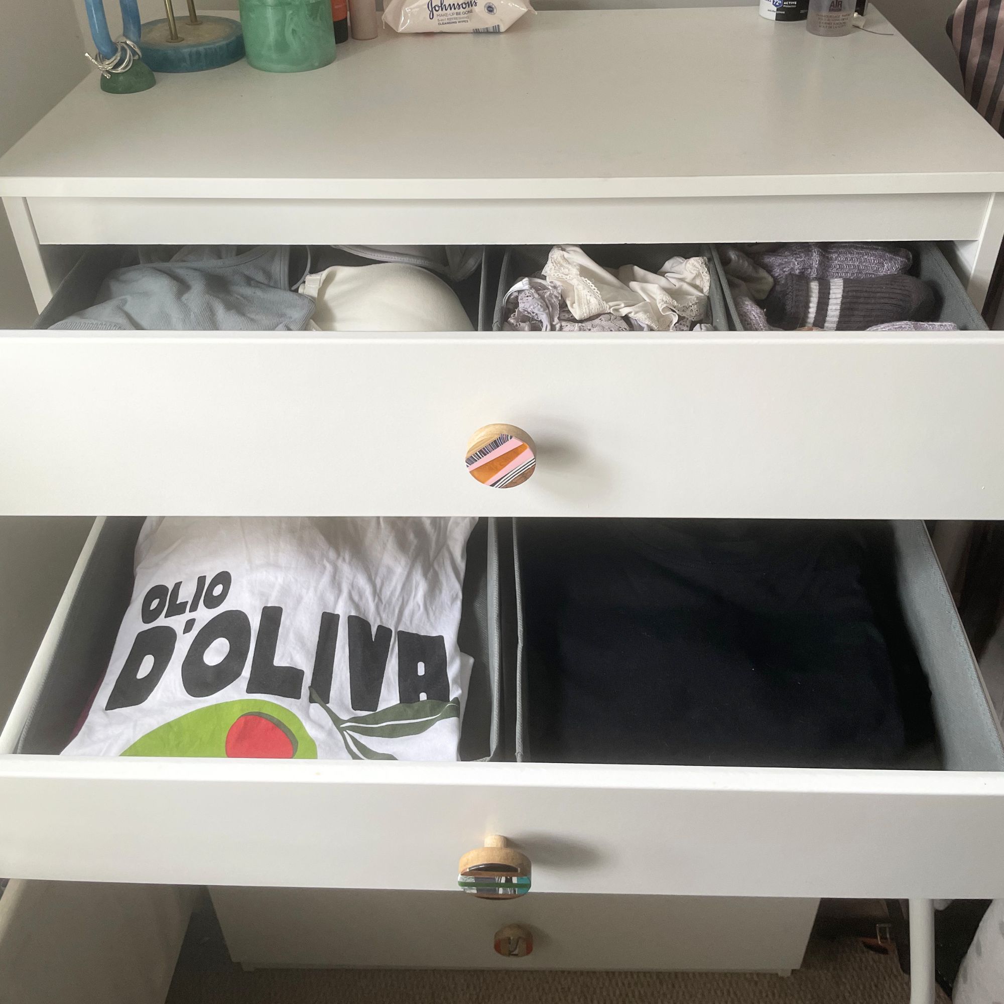 White chest of drawers with the top and middle drawers open, showing clothes organisers inside