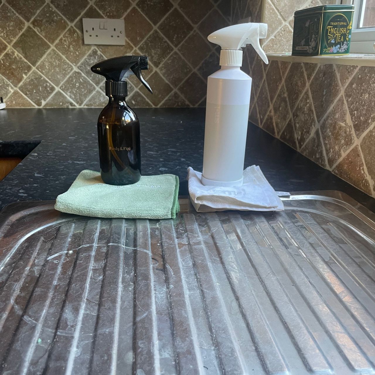 Purdy & Figg and Smol cleaning bottles in front of a dirty draining board